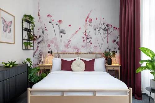 Hotelový pokoj s manželskou postelí před tapetou s růžovými květy, hotel Botanica, říjen 2025