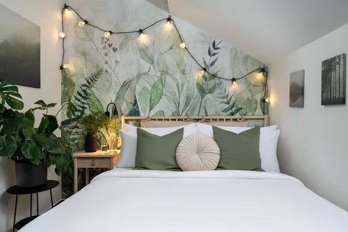 Podkrovní pokoj se zelenou listovou tapetou a světelnou girlandou, hotel Botanica, říjen 2025