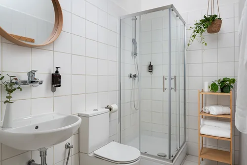 Koupelna pokoje s bílým obkladem a novým sprchovým koutem, hotel Botanica, říjen 2025