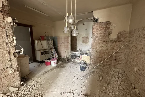 Kuchyň bytu během bourání, stěny otlučené na cihlu, květen 2023
