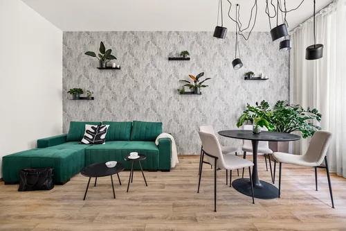 Apartmán se zelenou pohovkou, listovou tapetou a jídelním koutem, červenec 2023
