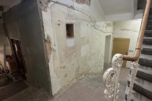 Podesta schodiště v přízemí domu Starobrněnská 13 s opadanou omítkou, prasklinami a odkrytou starou malbou, leden 2023
