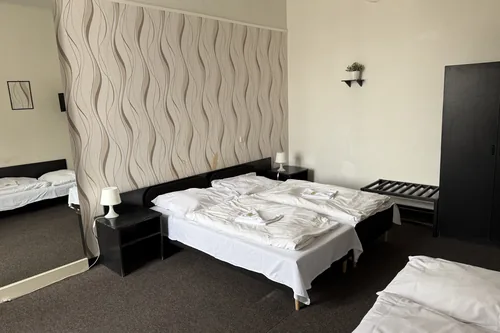 Pokoj původního hotelu s poškozenou vlnitou tapetou a velkým zrcadlem, březen 2025