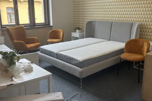 Pokoj se žlutou tapetou při zařizování, nová postel a křesla u okna, červenec 2025