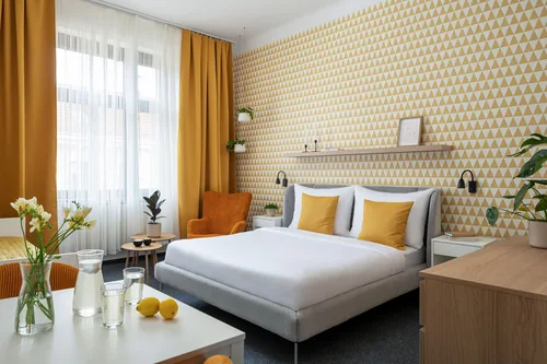 Hotelový pokoj se žlutou geometrickou tapetou a křeslem u okna, hotel Riverside, červenec 2025