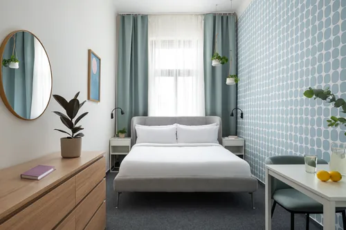 Úzký hotelový pokoj s postelí pod oknem a modrou tapetou, hotel Riverside, červenec 2025