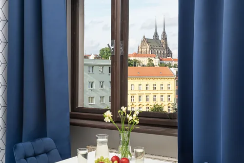 Stolek u okna pokoje s výhledem na katedrálu na Petrově, hotel Riverside, červenec 2025