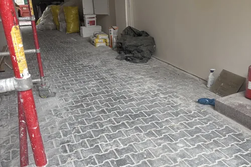 Průjezd domu během stavebních prací, lešení a pytle s materiálem, květen 2025