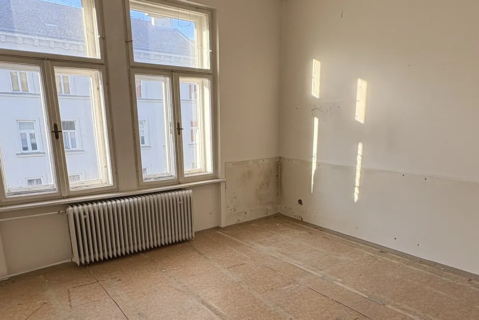 Před rekonstrukcí: prázdný pokoj do ulice s holými zdmi a starou podlahou, Hlinky 28a, srpen 2025